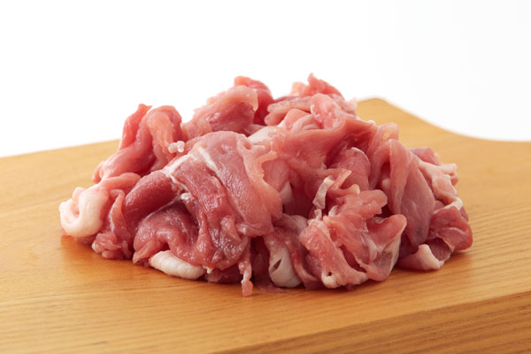 豚肉の細切れを、まな板の上の盛り上げて1カット、白い皿に盛り上げて1カットの2点。フリー画像。背景は白、用途は料理のレシピ等。