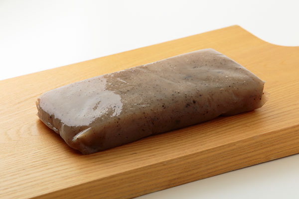 木製のまな板にのせて黒いこんにゃく1カット