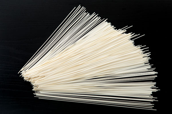 極細のソーメン（乾麺）を黒い木目の板に扇の形に広げた画像