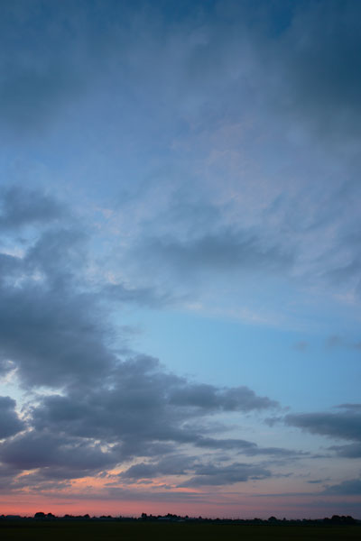 夕暮れの残照が残る空の写真素材。地平線は夕焼け、上空はかすかに夕焼けの赤を遷す雲、濃紺の空