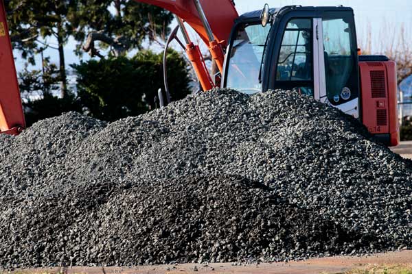 盛り上げた砕石の山、背後に作業用重機バックホウ