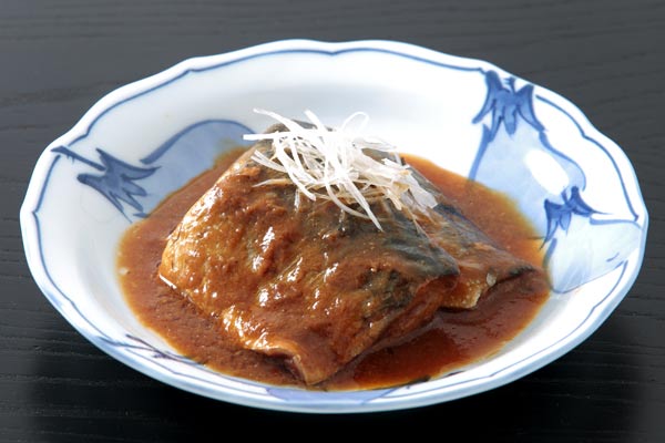 皿に盛りつけた鯖の味噌煮2切れ、上に白髪ネギを添えて。背景は黒い木目のお盆。