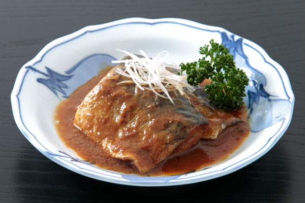 鯖の味噌煮2切れを皿に盛りつけ、上に白髪ネギを、横にパセリを添えた。背景は黒い木目のお盆。