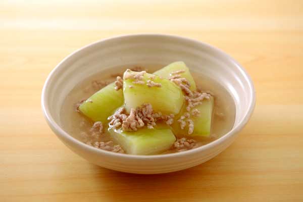 小鉢に盛りつけたひき肉あんかけの冬瓜料理。明るい木目のテーブルに置いて1カット